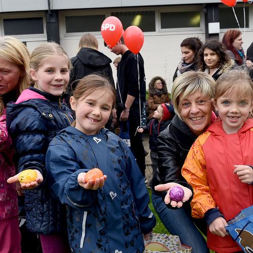 Gruppe von Kindern und Erwachsenen bei einer Veranstaltung, einige Kinder halten bunte Eier in den H&auml;nden.