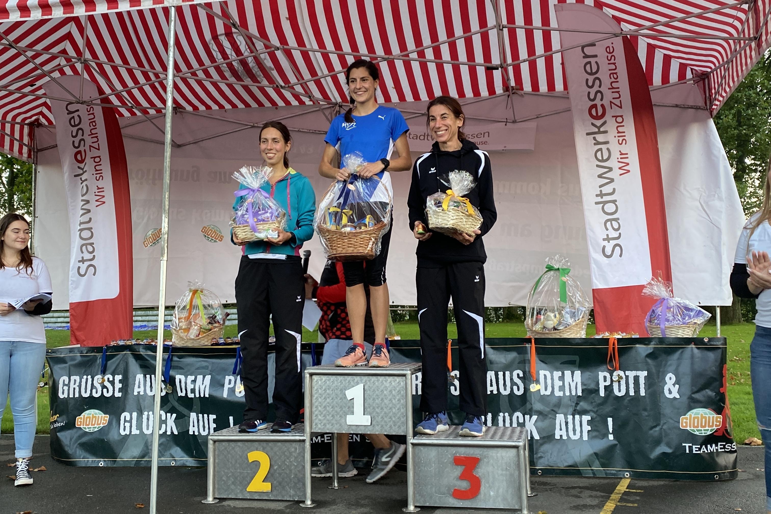 Drei Sportlerinnen stehen auf dem Siegertreppchen, während sie Medaillen und Preise präsentieren.