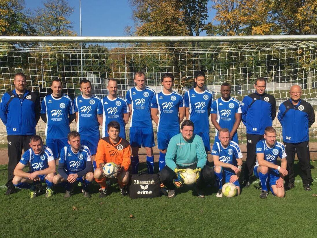 Mannschaftsfoto einer Fußballmannschaft in blauen Trikots vor einem Tor auf einem grünen Platz.