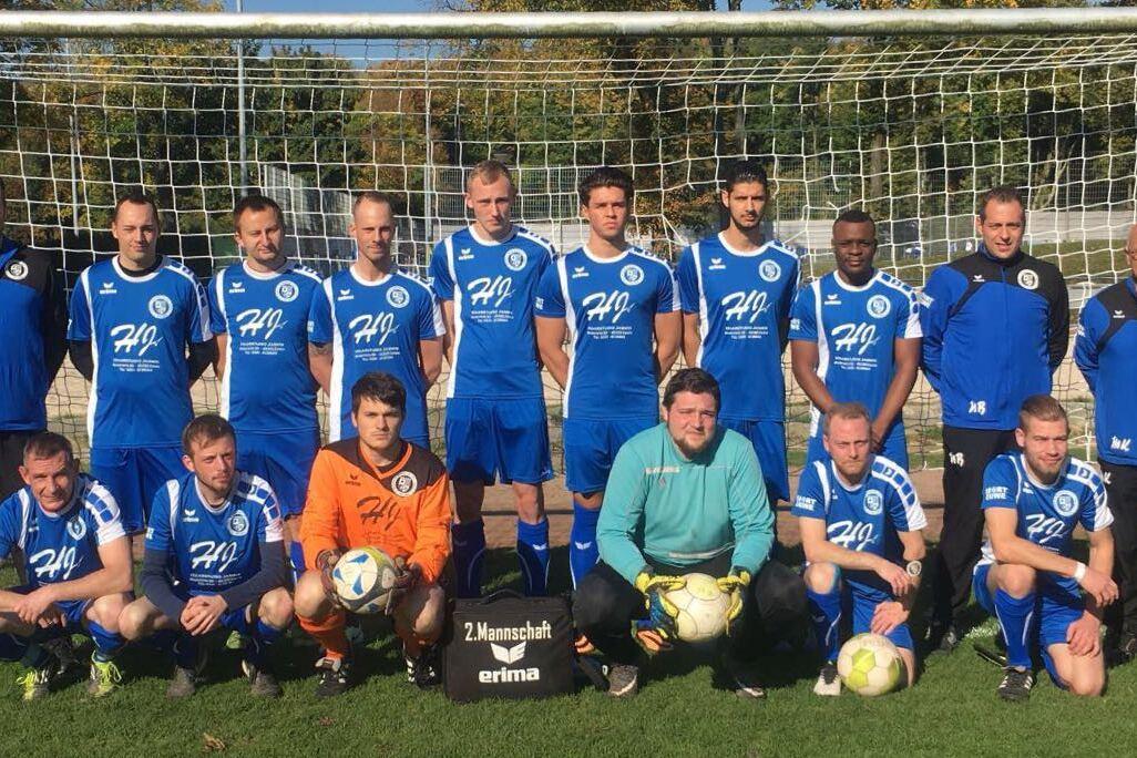 Mannschaftsfoto einer Fußballmannschaft in blauen Trikots vor einem Tor auf einem grünen Platz.