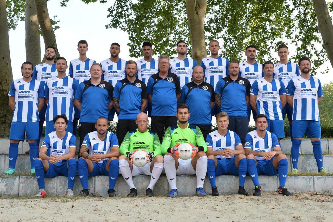 Mannschaftsfoto einer Fu&szlig;ballmannschaft in blauen und wei&szlig;en Trikots, auf einer Treppe im Freien posierend.