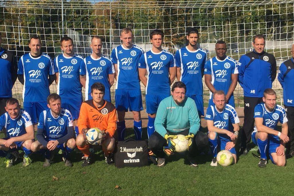 Mannschaftsfoto einer Fußballmannschaft in blauen Trikots vor einem Tor auf einem grünen Platz.