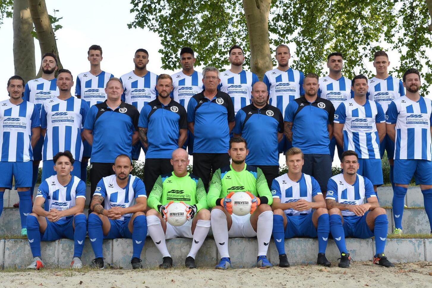 Mannschaftsfoto einer Fu&szlig;ballmannschaft in blauen und wei&szlig;en Trikots, auf einer Treppe im Freien posierend.