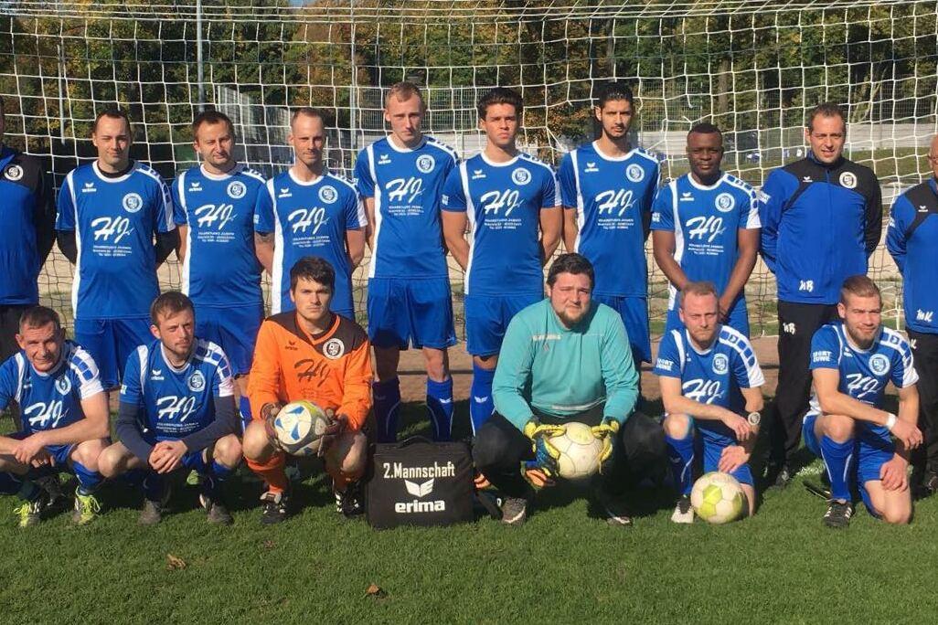 Mannschaftsfoto einer Fußballmannschaft in blauen Trikots vor einem Tor auf einem grünen Platz.