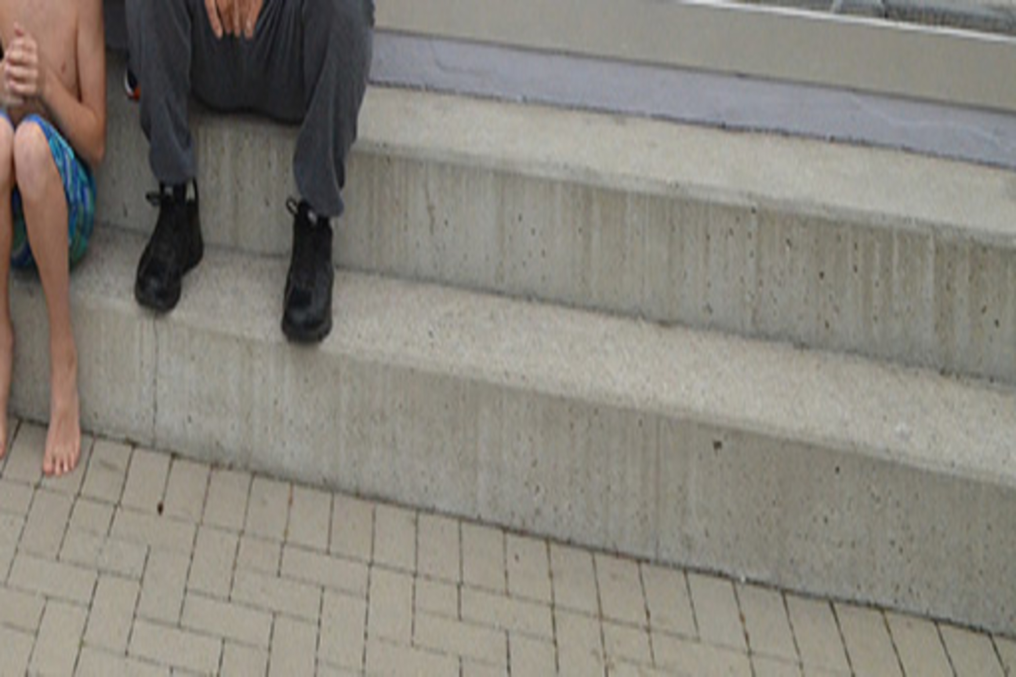 Gruppe von Menschen in sportlichen Outfits posiert fr&ouml;hlich in einem Freiluftbereich mit Bannern und Maskottchen.