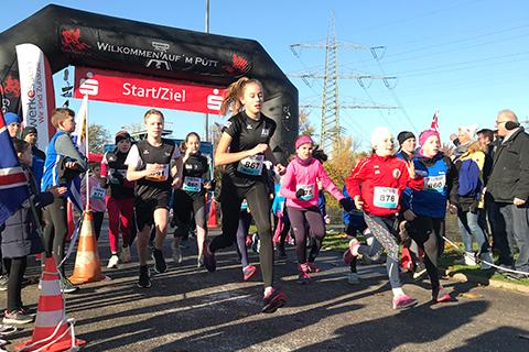 Start eines Kinderlaufs mit mehreren laufenden Teilnehmern unter einem gro&szlig;en Startbogen bei klarem Wetter.