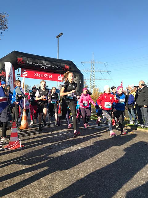 Start eines Kinderlaufs mit mehreren laufenden Teilnehmern unter einem gro&szlig;en Startbogen bei klarem Wetter.